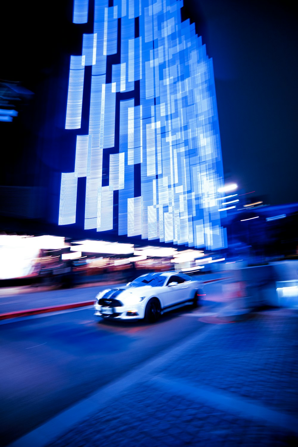 a car driving on a road by a tall building