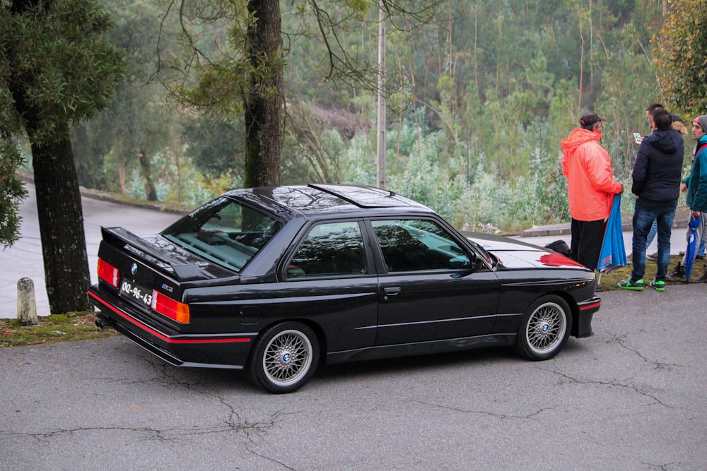 um carro estacionado em uma estrada com pessoas em pé ao redor