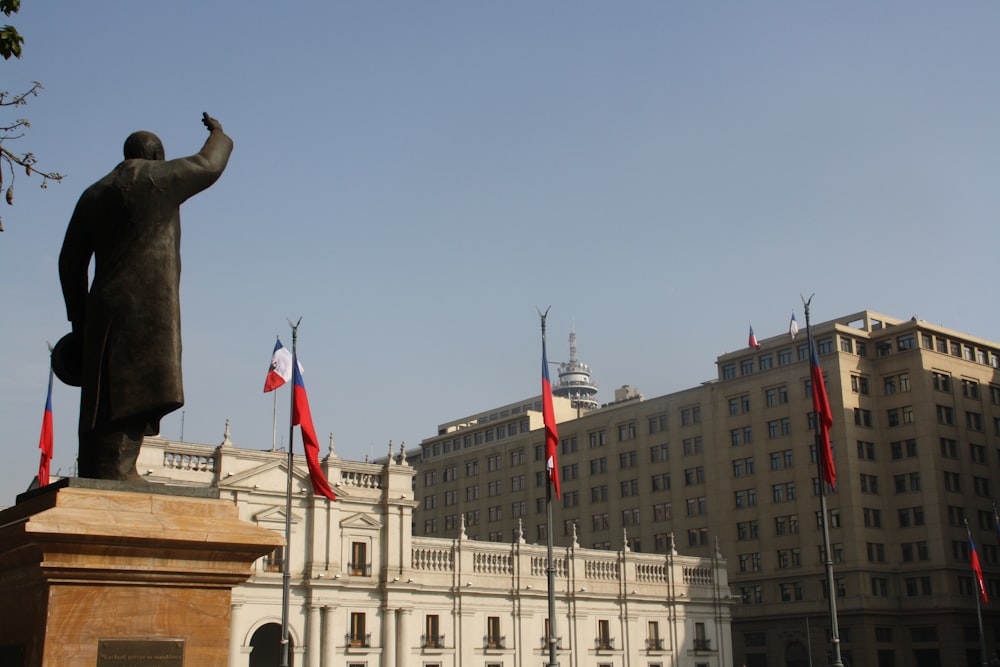 una estatua de una persona sosteniendo una bandera frente a un edificio