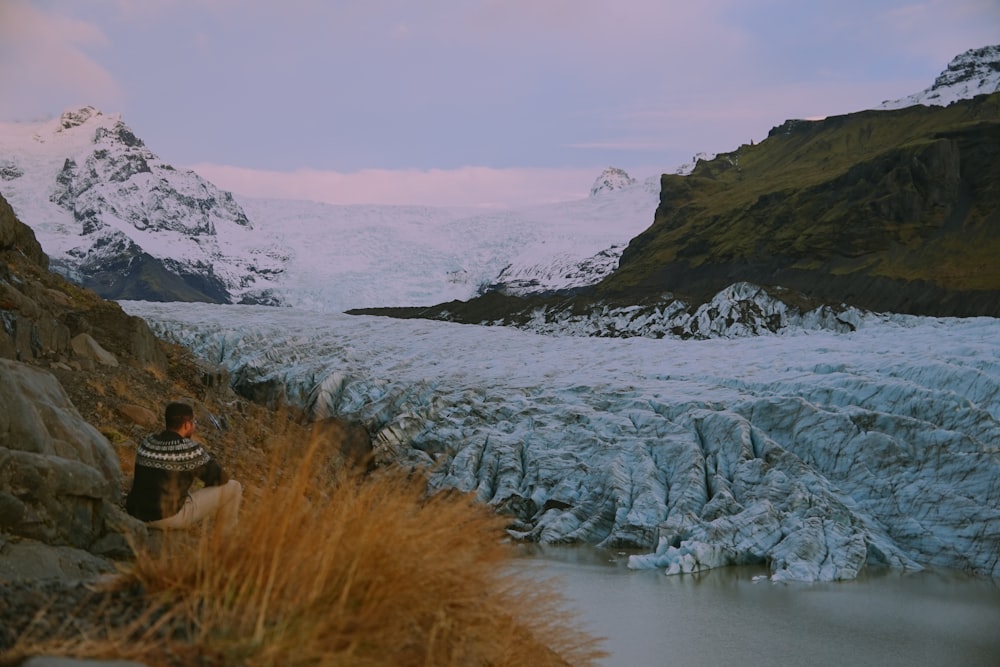 Una persona sentada en una roca en un lugar nevado