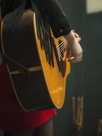 a person holding a black and yellow guitar