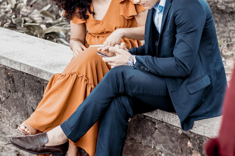 a man and woman sitting on a rock