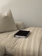 A selection of plush cushions and throws in neutral colors arranged on a minimalist sofa.