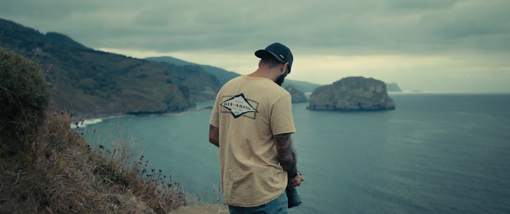 a man standing on a hill overlooking a body of water