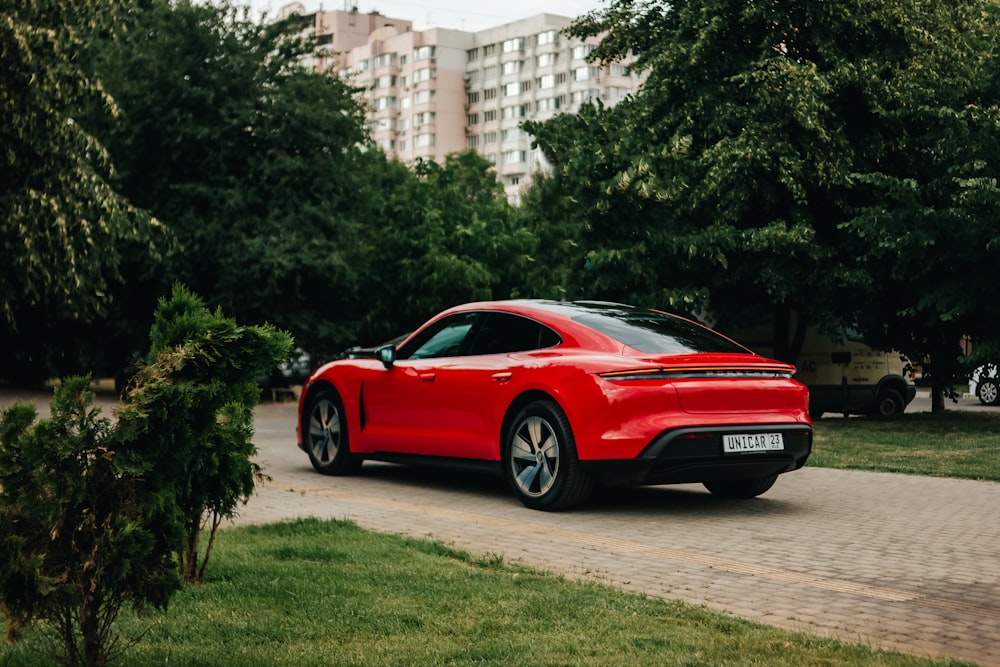 a red sports car parked on a road with trees and grass