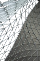 A geometric glass and steel roof structure with triangular panels forming a lattice pattern. The design creates a modern and intricate architectural element.