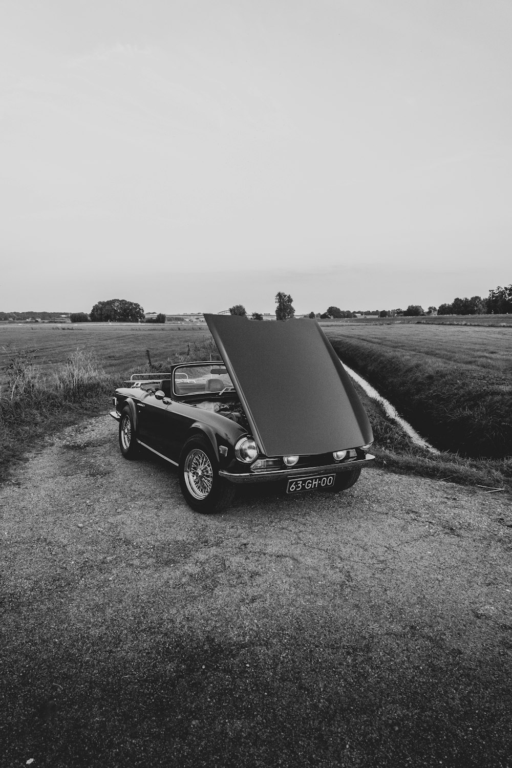 a car with a covered hood parked in a field