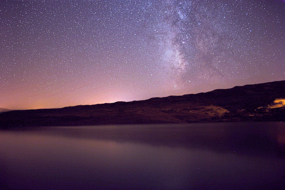 a body of water with a hill in the background