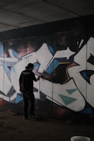 Close-up of a graffiti artist painting a neon-lit wall at night.
