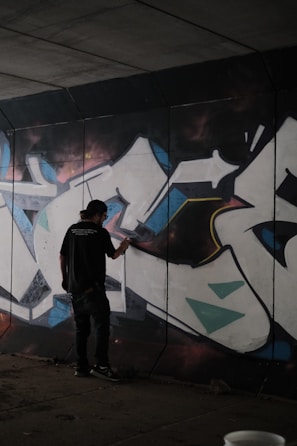 Close-up of a graffiti artist painting a neon-lit wall at night.