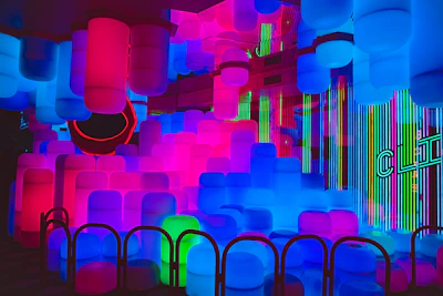 Colorful 3D printed objects glowing softly in a modern workshop bathed in dark tones and vibrant neon highlights.