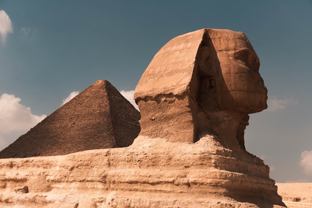 a large rock formation with Great Sphinx of Giza in the background