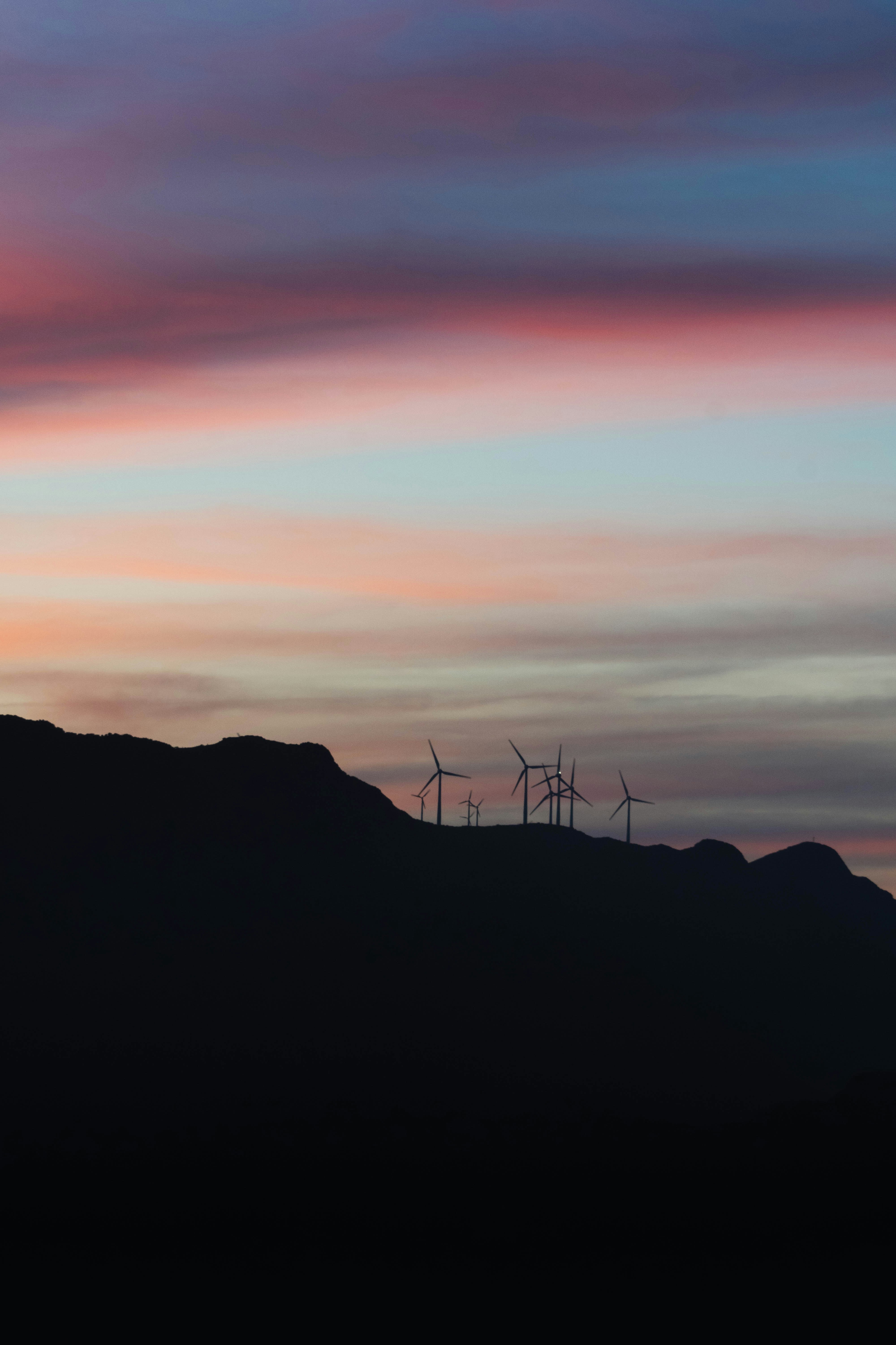 a group of wind turbines on a hill