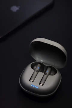 Close-up of wireless Bluetooth earbuds with a glowing blue charging case