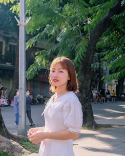 A cheerful young woman wearing a flowing summer dress in a sunlit urban setting