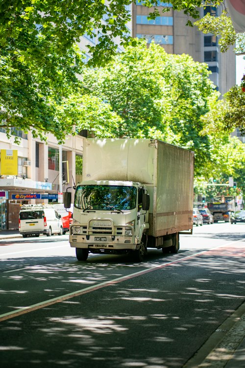 Moving truck driving through a tree-lined city street
