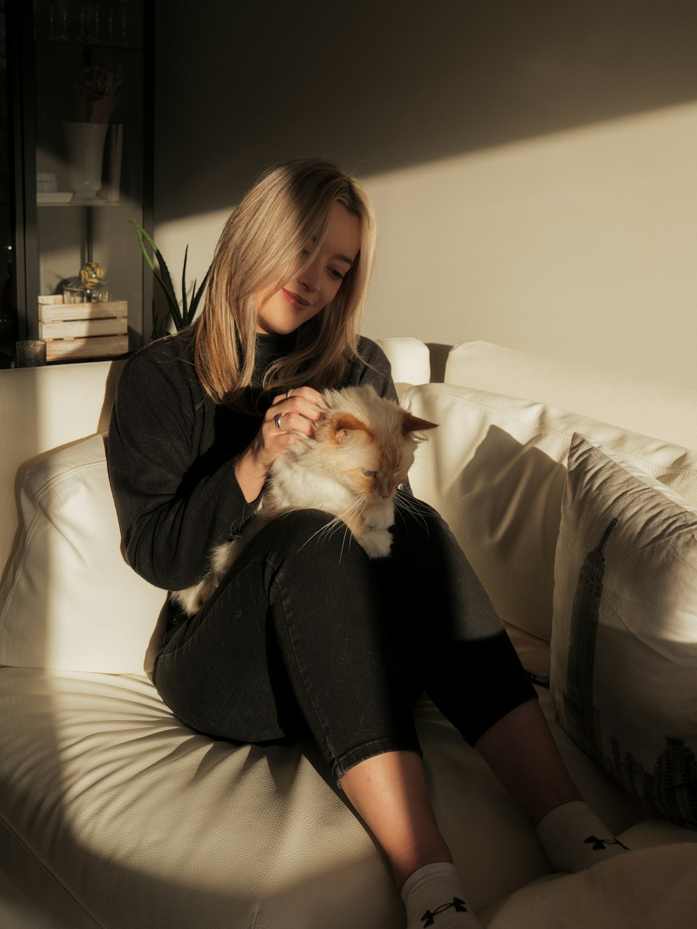 a woman sitting on a couch holding a cat