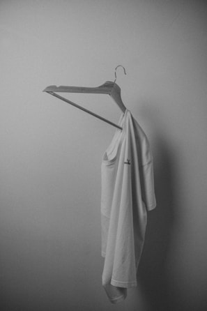 Minimalist white cotton t-shirt laid flat on a light wooden surface.