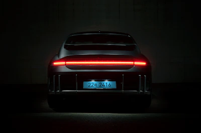 Rear view of a car with illuminated license plate and sleek LED tail lights by Plaser.