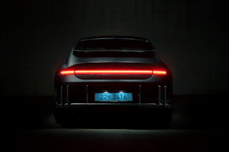 Rear view of a car with illuminated license plate and sleek LED tail lights by Plaser.