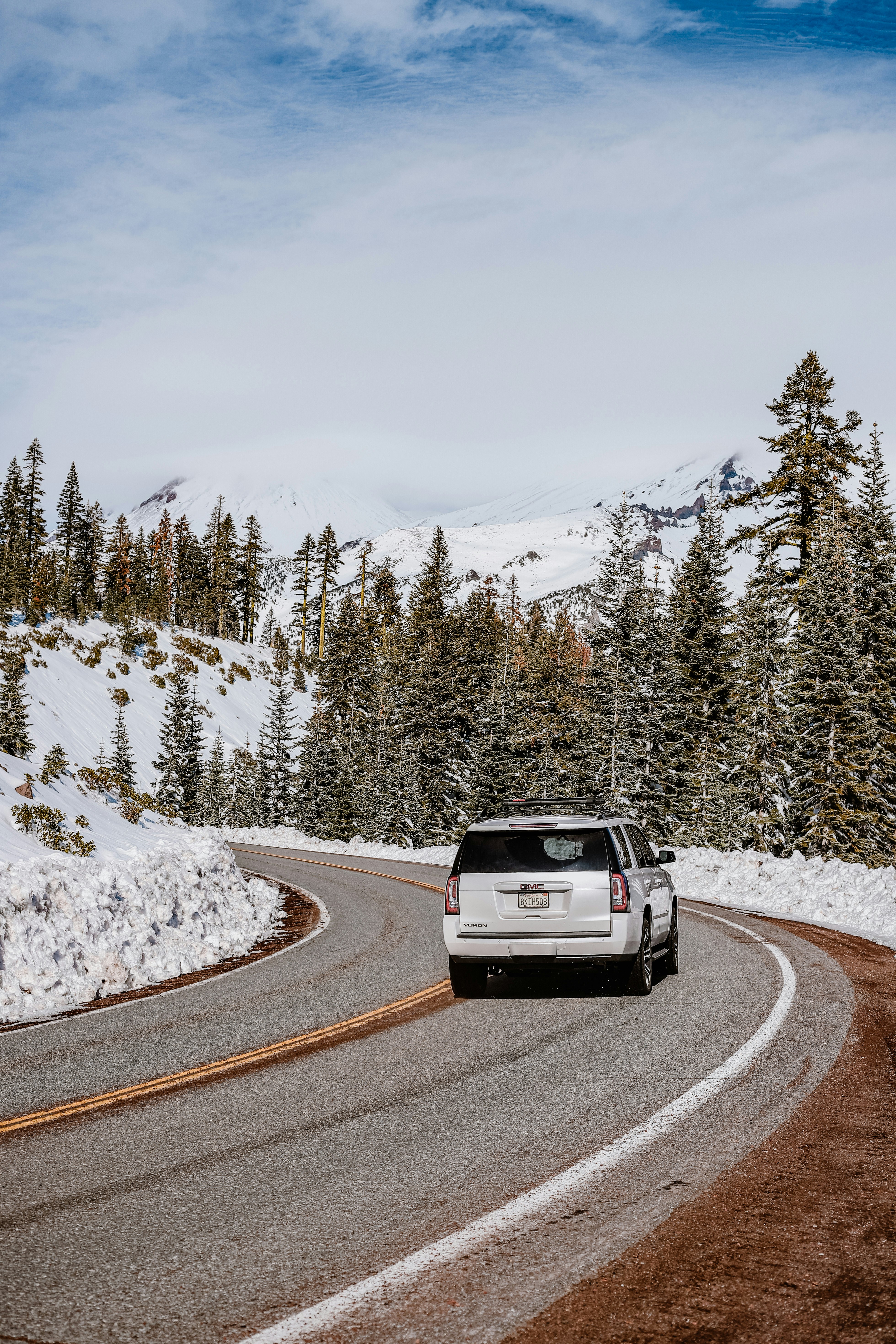 a white car driving on a road with snow on the side