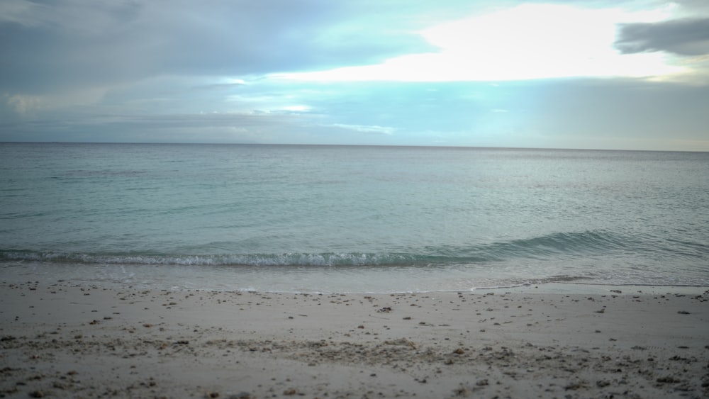 a beach with waves and a cloudy sky