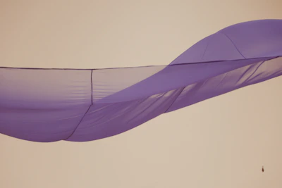 Atmospheric image of flowing silk fabric illuminated by gentle purple light.