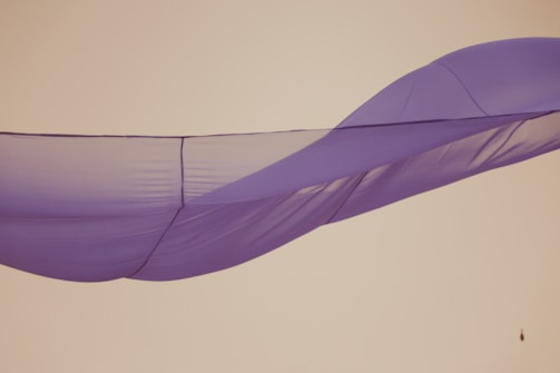 A serene shot of a muted lavender fabric draped elegantly over a charcoal backdrop.