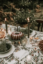 A festive outdoor table set with colorful dishes and palm trees decorated with Christmas lights in the background.