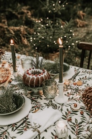 A festive outdoor table set with colorful dishes and palm trees decorated with Christmas lights in the background.