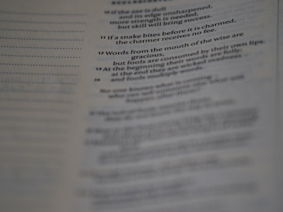 A close-up of a book or document with printed text. The focus is on a specific section where numbered verses or paragraphs are visible, conveying sayings or proverbs.