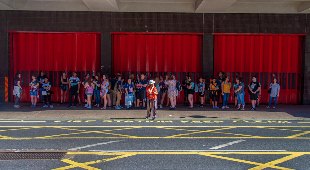 a group of people standing in front of a red wall