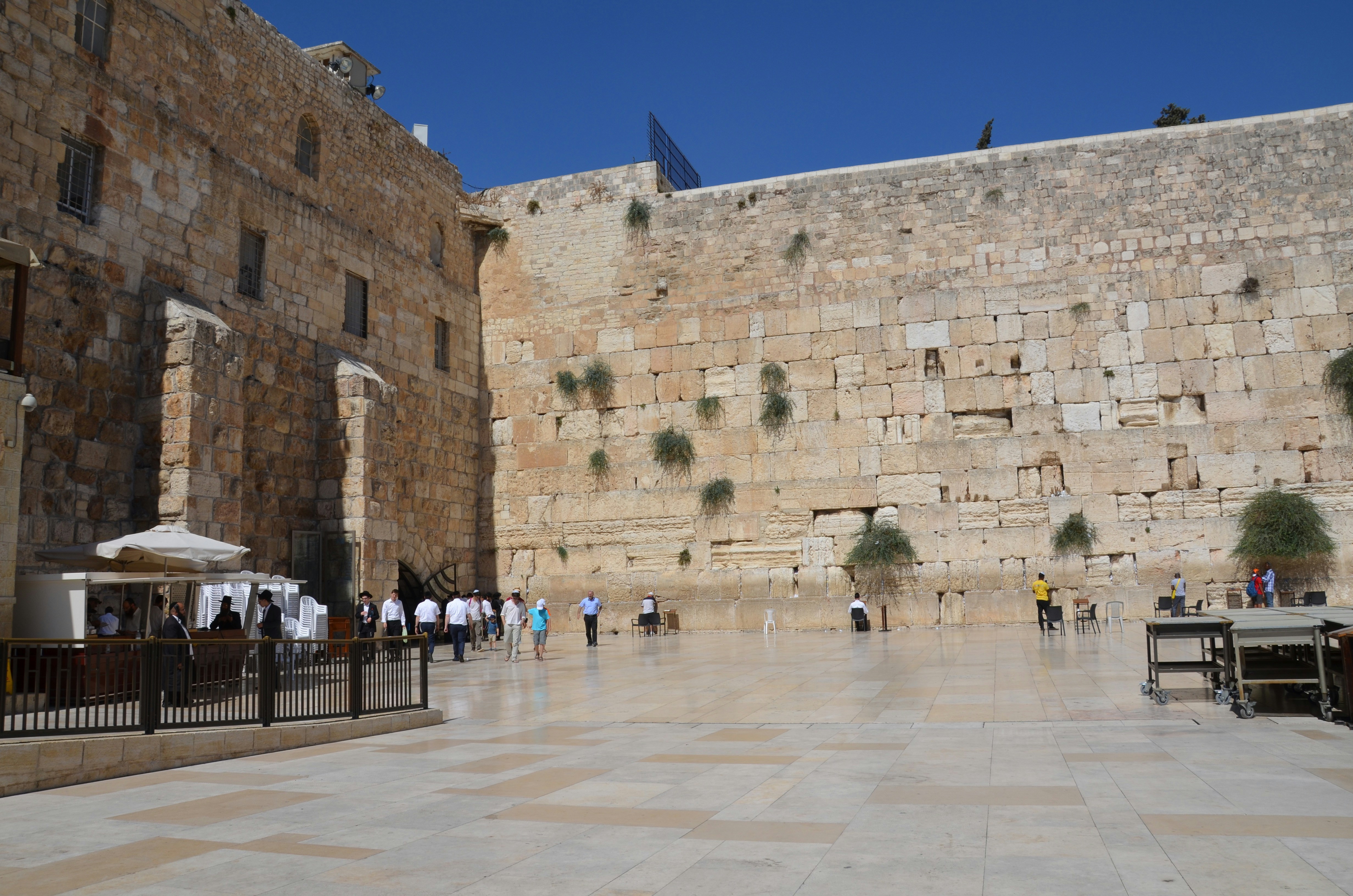a group of people walking around a large stone building with Western Wall in the background