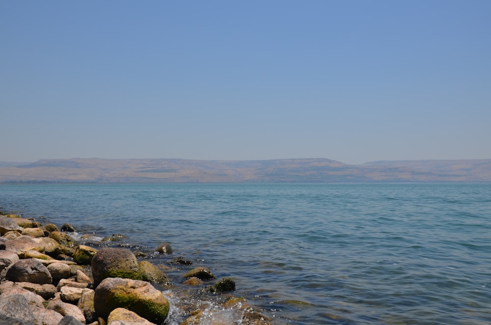 a rocky beach with a body of water in the background