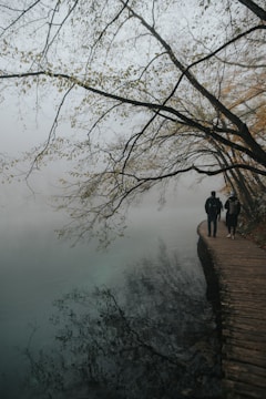 Two walkers chatting with locals beside a scenic lakeside path.