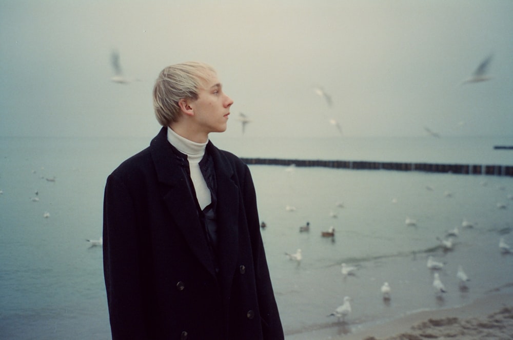 a man in a suit looking at birds on the water