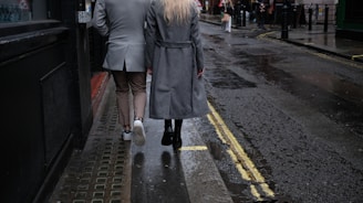 a man and woman walking down a wet sidewalk