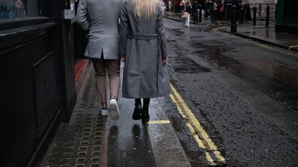 a man and woman walking down a wet sidewalk