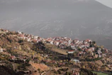 A peaceful mountain village with terracotta roofs and green hills in the background.