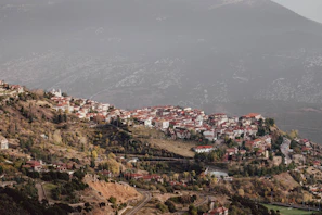 A peaceful mountain village with terracotta roofs and green hills in the background.