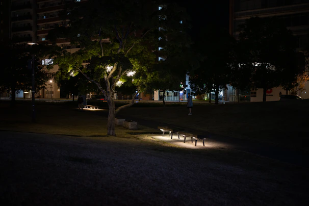 Solar garden light illuminating a cozy park bench at dusk with lush greenery surrounding.