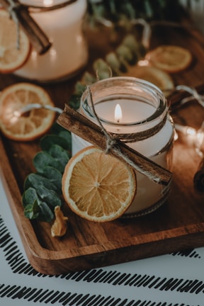 A cozy candle surrounded by dried citrus peels and potpourri in warm lighting.