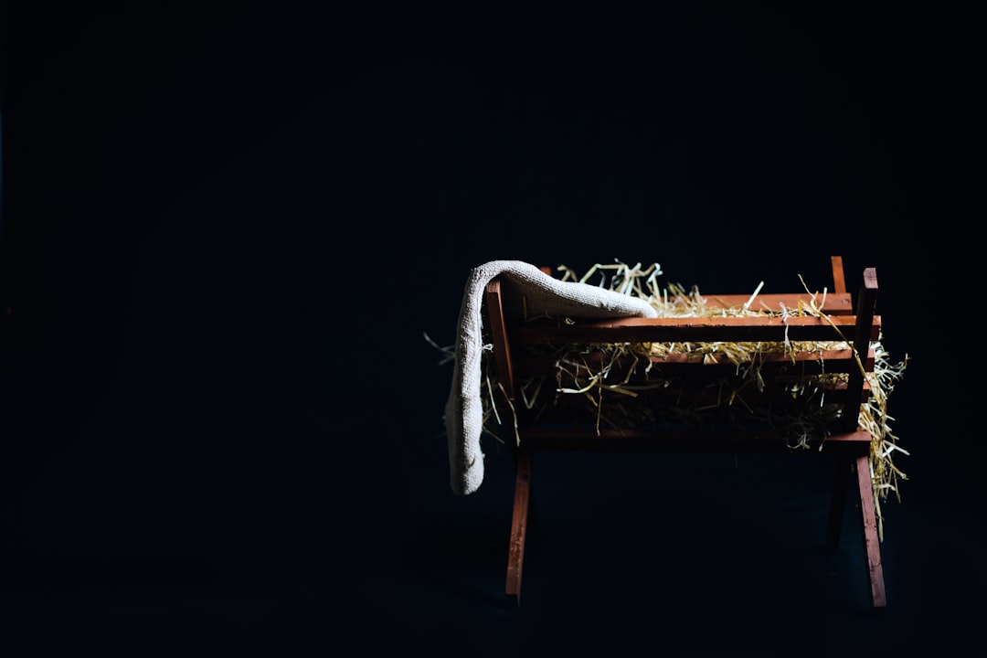 A wooden manger filled with straw and a piece of burlap on a black background.