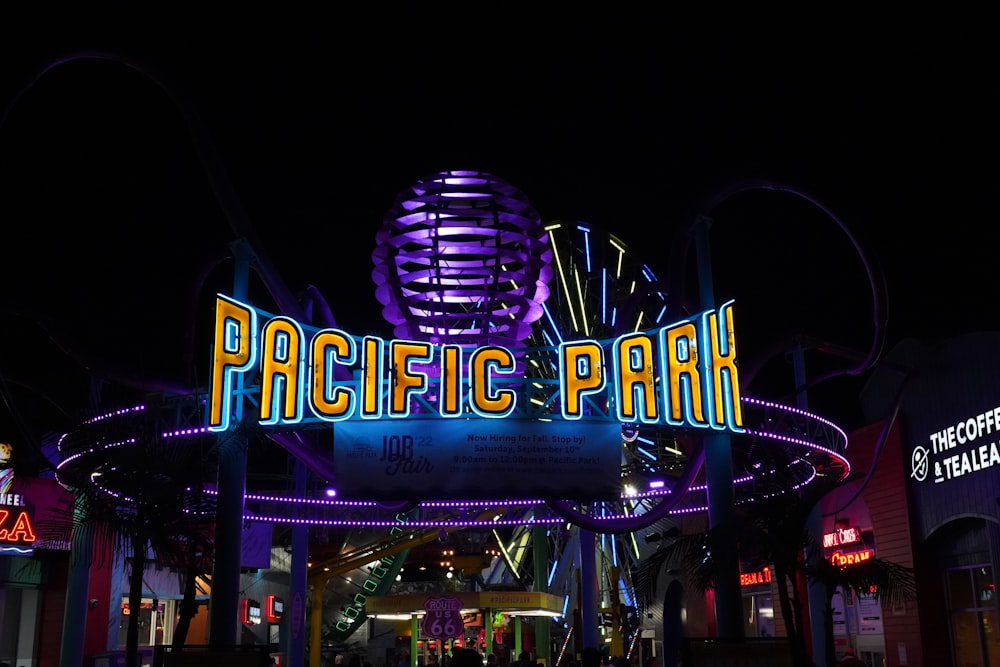 a neon sign with a ferris wheel in the background