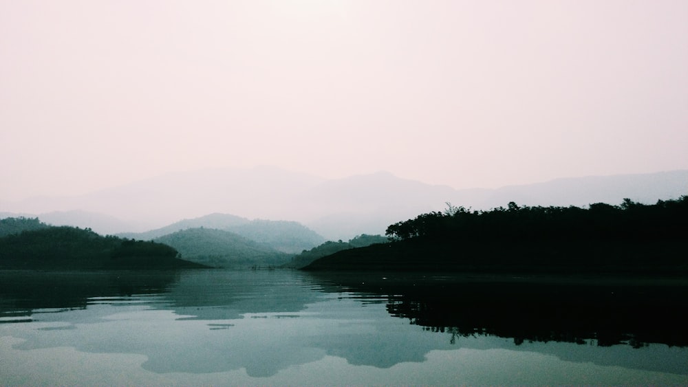 a body of water with trees and hills in the background