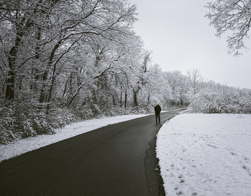 a person walking on a road with snow on the side