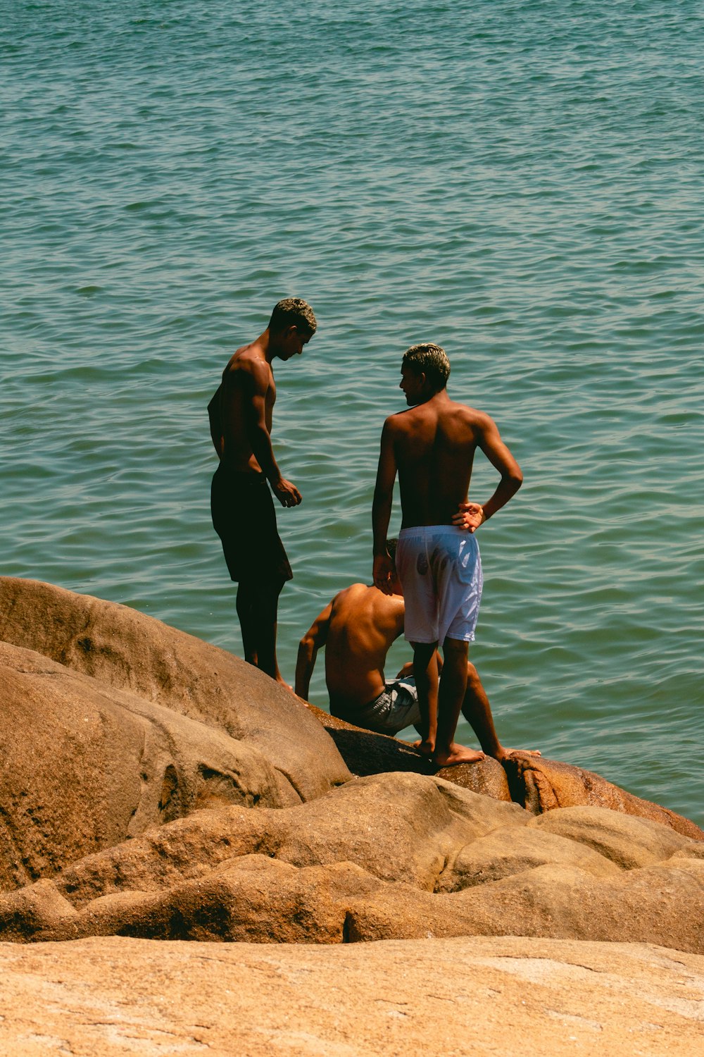 a group of men standing on rocks by the water