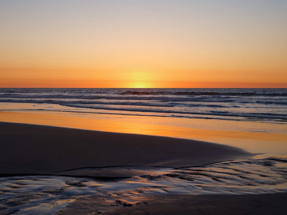 a beach with waves and a sunset