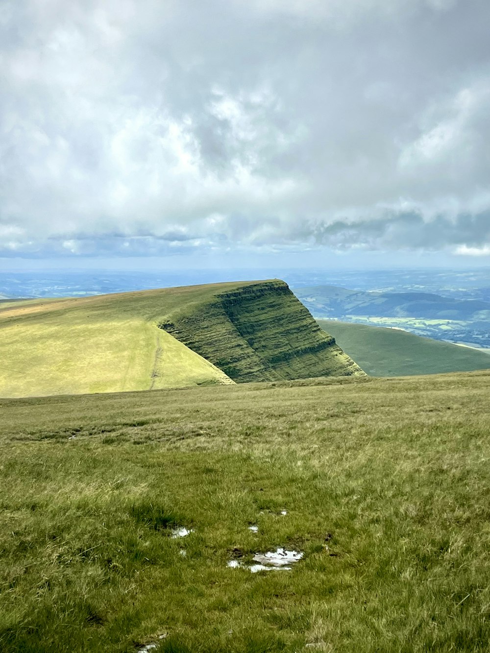 a grassy hill with a body of water in the background