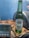 A Heineken Silver beer bottle stands on a wooden surface next to a digital thermometer. The thermometer displays several temperature readings. The background is a soft blue color, enhancing the refreshing theme.